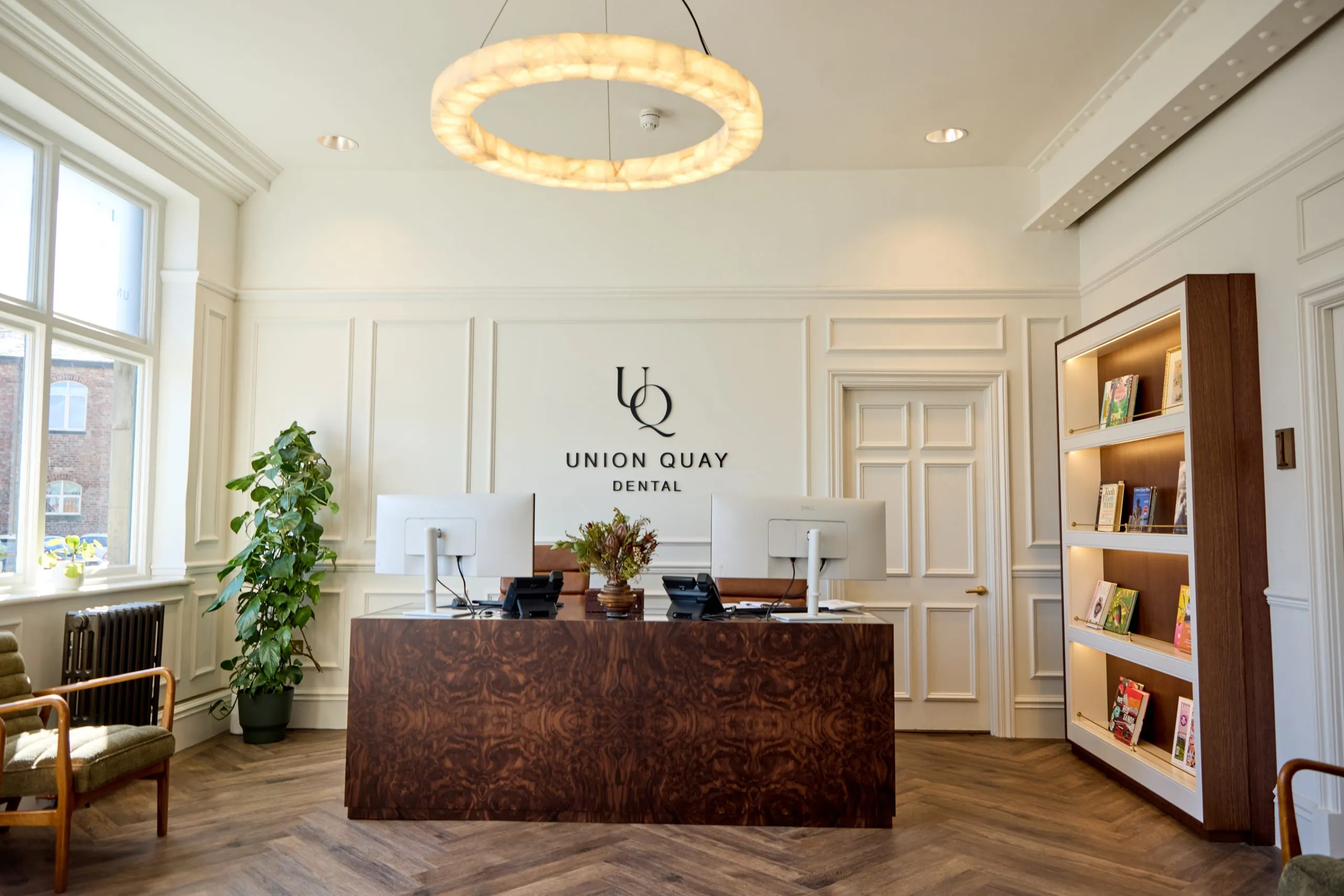 Panelled reception with copper desk and library shelving at Union Quay Dental