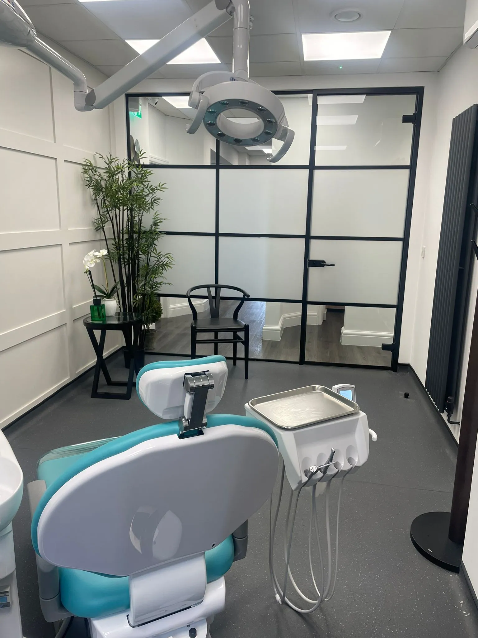 Teal dental chairs behind bespoke glazed screens at Infinity Dental Clinic, Leeds
