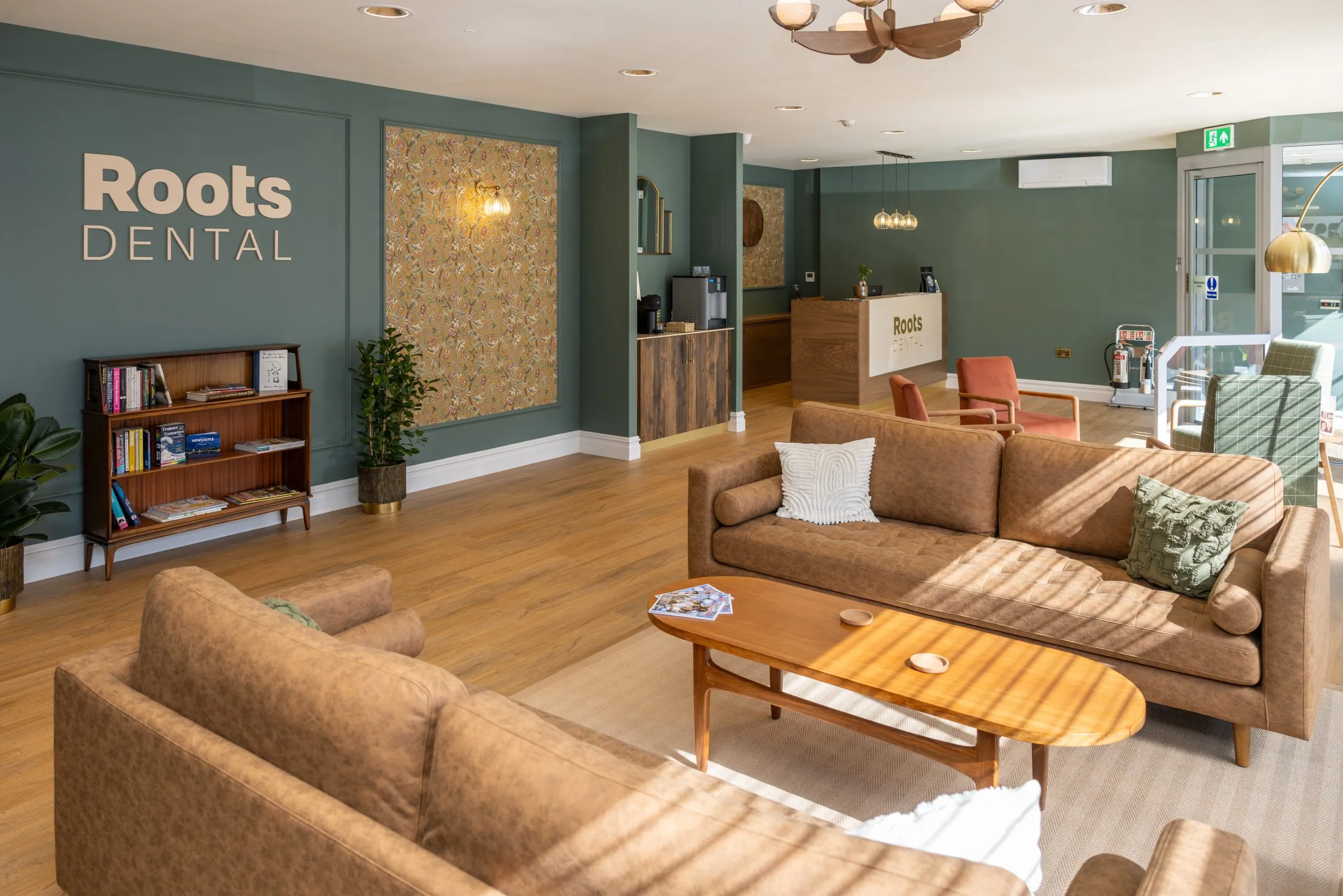 Waiting lounge with tan leather sofas and green panelling at Roots Dental, Morpeth