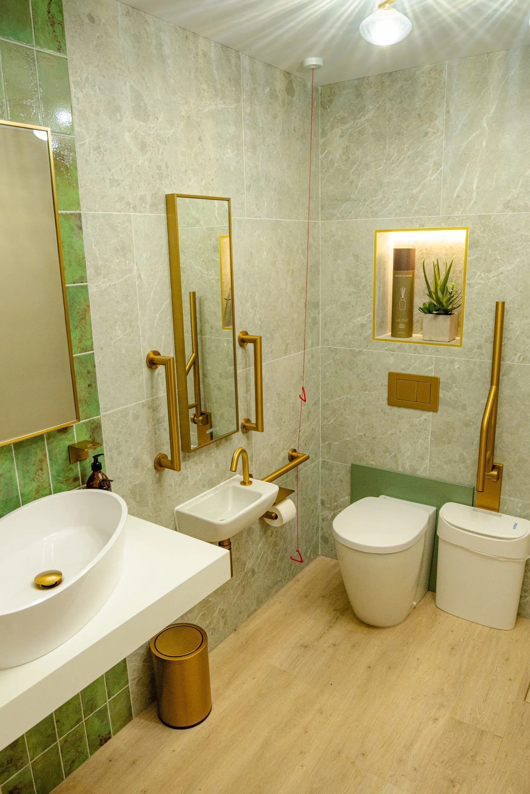 Accessible washroom with green tiling and brass rails at Alma Dental, North Shields