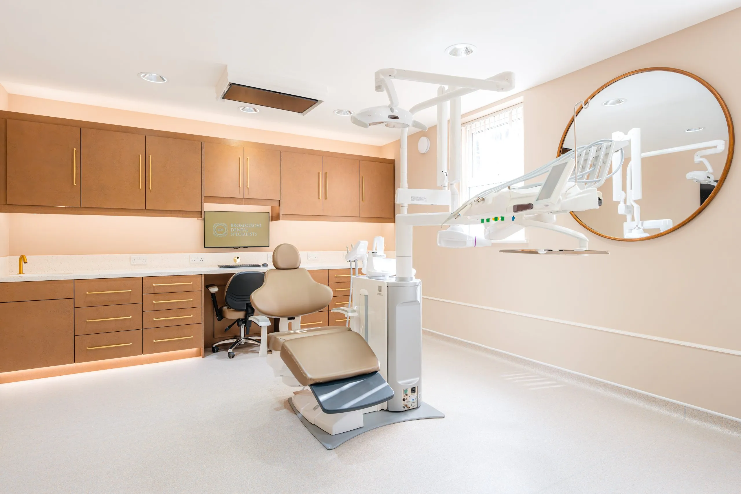 White dental surgery with wall-mounted delivery unit and bespoke storage at Bromsgrove Dental Specialists